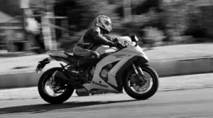 Dynamic black and white shot of a motorbike rider on a Kawasaki in motion.
