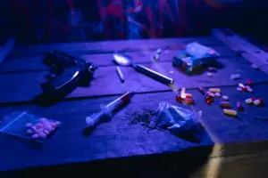 A moody scene displaying drugs, a gun, and smoke under dramatic lighting.