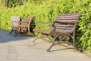 Detail dřevěných laviček ve slunném městském parku v Uzbekistánu, ideální pro relaxaci.