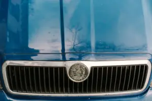 Detailní detail modré mřížky a kapoty veteránů s výrazným kovovým znakem.