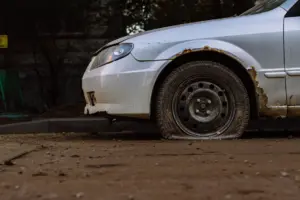 Detailní záběr na zrezivělé auto s prázdnou pneumatikou zaparkované na ulici v Moskvě, ilustrující městský úpadek.